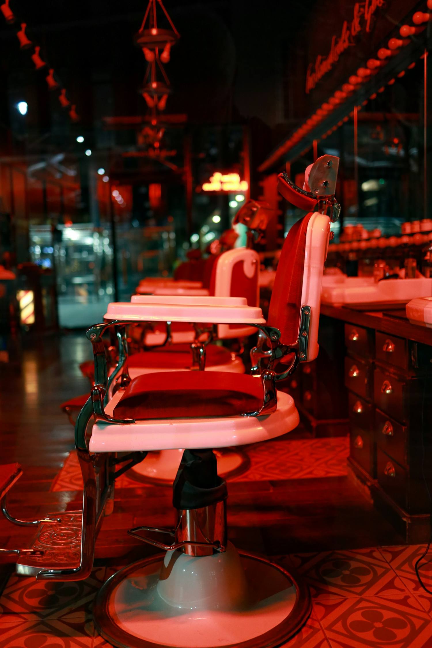 Barber chairs lit in red inside the shop