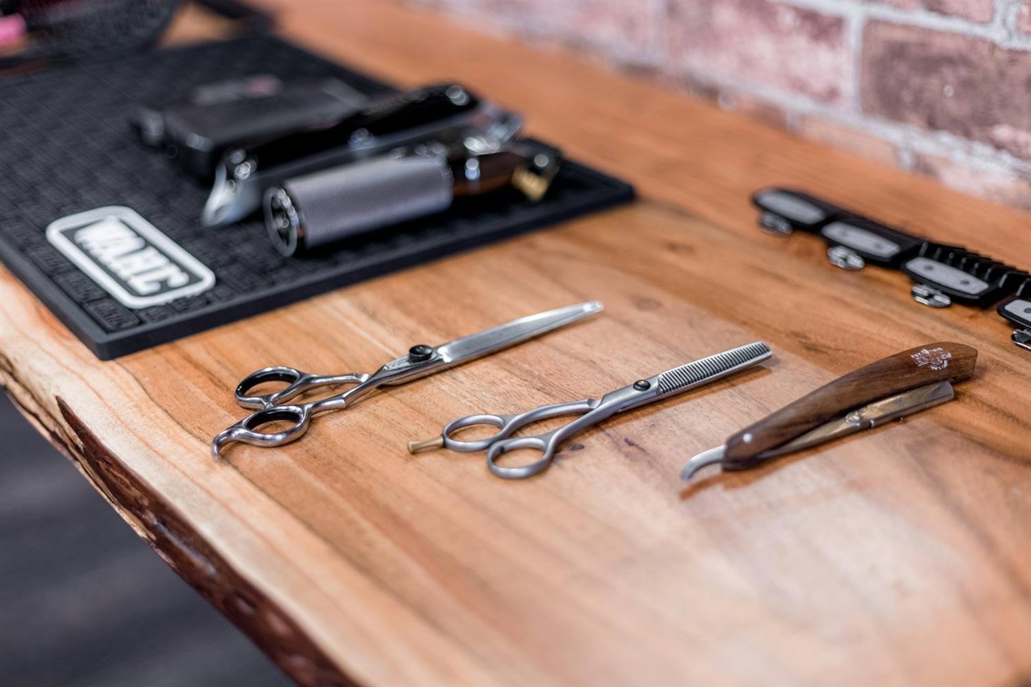 Scissors and a cut-throat razor laid out on a wooden counter